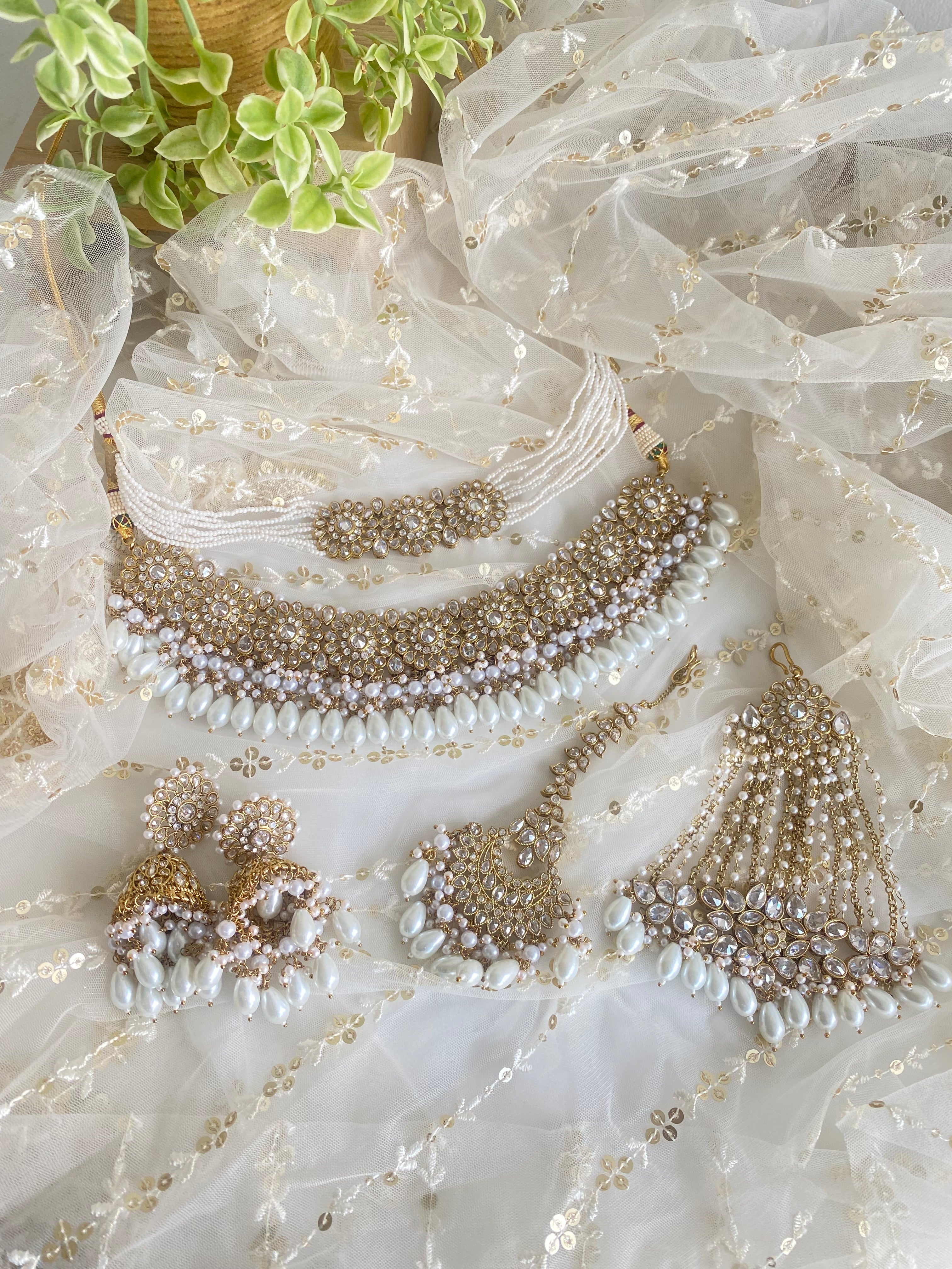 Nargis our most elegant set has bib necklace, choker, jhumkaas, tikka and jhumar is optional, its has gold base with white stone and pearl. We do customized bangles. Contact on whatsapp +13137271045